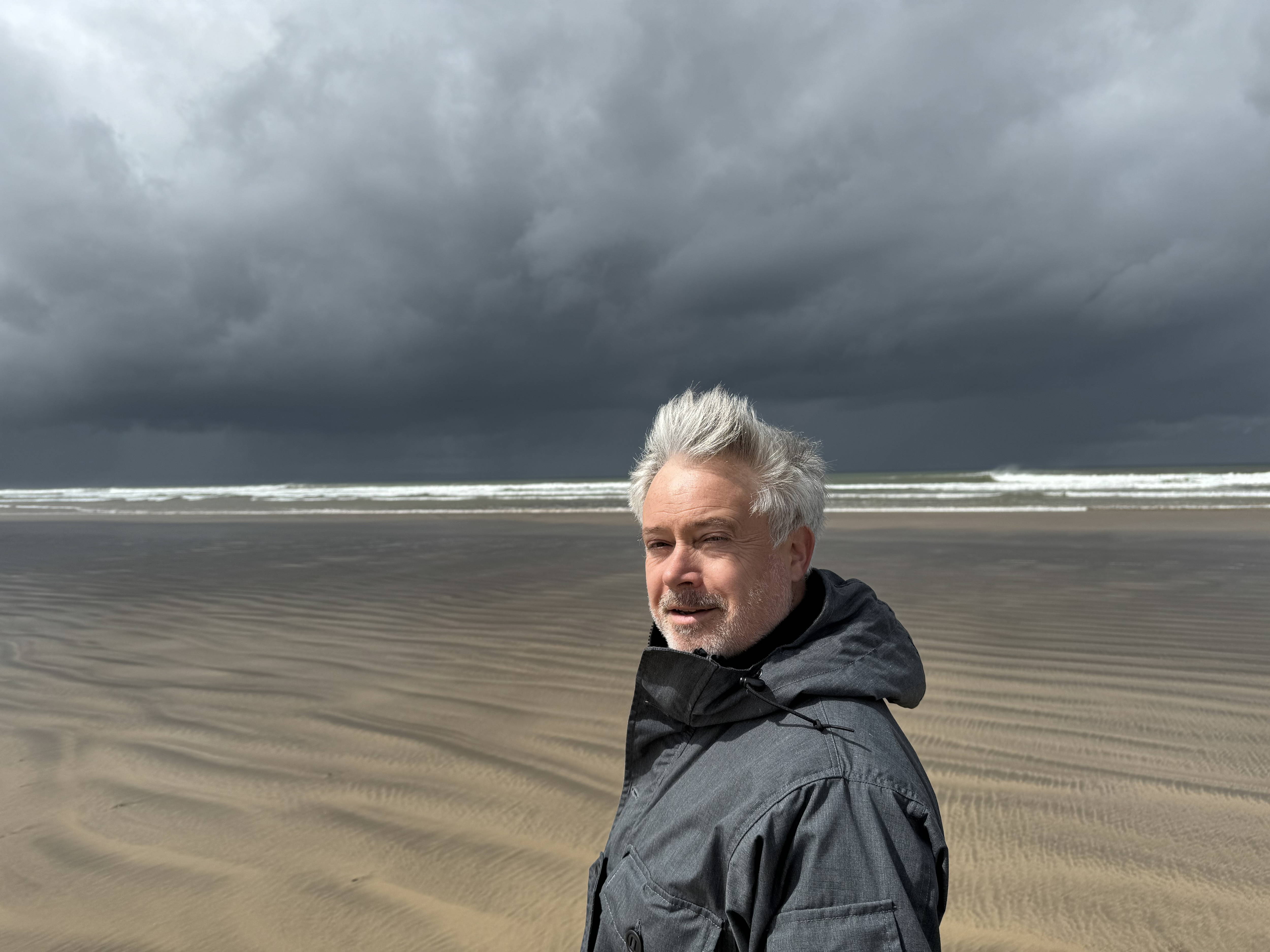 An image of Rob Deere in front of a beach scene.